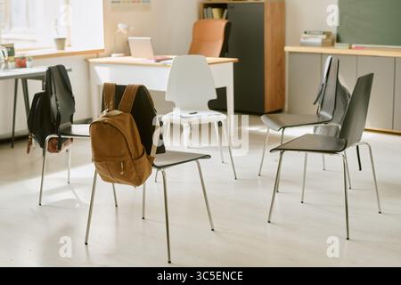 Empty Classroom Showing Backpacks Hanging on Chairs during School Day Stock Photo