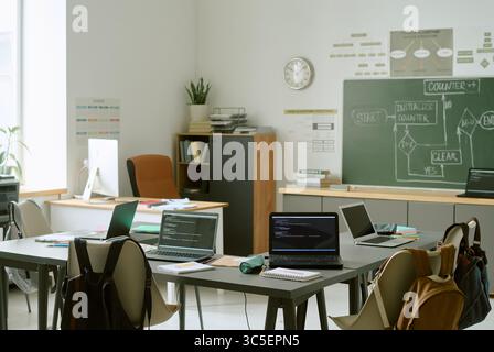 Empty Classroom with Laptops Displaying Programming Code during School Lesson Stock Photo