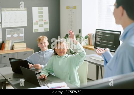 Asian Girl and Caucasian Boy Using Laptops While Participating in Coding Class Stock Photo