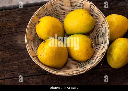 Ripe mango tropical fruit in basket on wooden table at mangoes farm Stock Photo