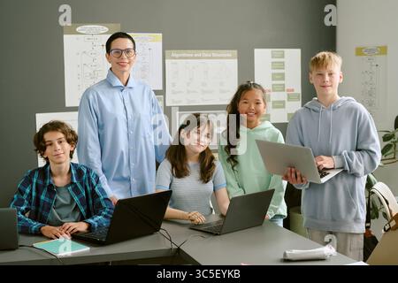 Group of Diverse Teenagers Collaborating on Laptops in Classroom Setting Stock Photo