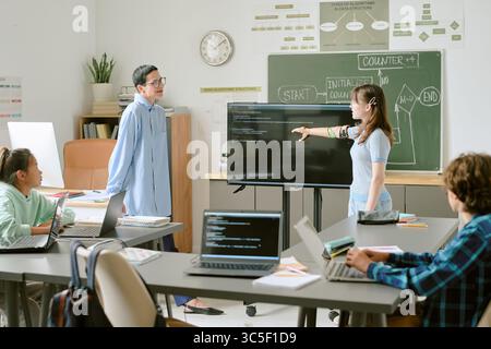 Diverse Teenagers Collaborating on Coding Project in Modern Classroom Setting Stock Photo
