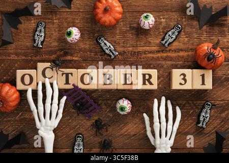 A skeleton's hands reach for the 31 October inscription. Halloween vibes, pumpkins, eyes, bats, spiders. Stock Photo