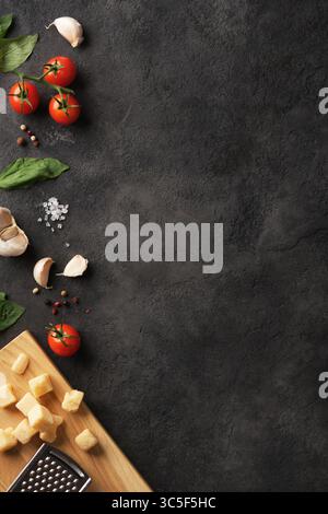 Vertical banner with fresh Italian ingredients with basil, tomatoes, garlic and cheese on dark background. Space for your text. Stock Photo
