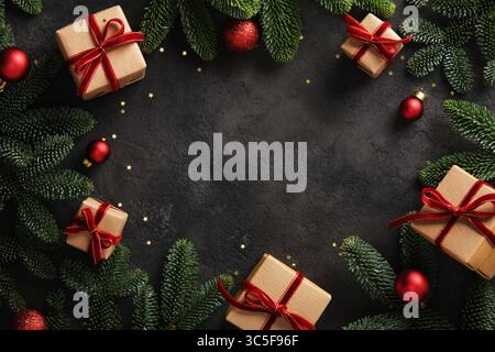 Christmas frame with gift boxes with red ribbons and pine branches on dark background. Place for your text. Stock Photo
