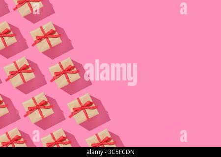 Banner with pattern of brown gift boxes on with red bows on pink background. Copyspace. Stock Photo