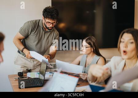Team collaborating in an office setting on important paperwork and laptops Stock Photo
