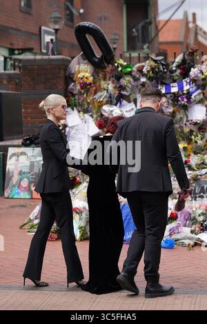 The family of Ozzy Osbourne (left to right) Kelly, Sharon and Jack Osbourne, view the messages and floral tributes left at the Black Sabbath Bridge bench on Broad Street in Birmingham in memory of Black Sabbath frontman Ozzy Osbourne, as his body is brought back to his home city for a procession following his death last week aged 76. Picture date: Wednesday July 30, 2025. Stock Photo