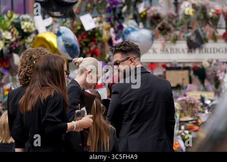 The family of Ozzy Osbourne, Kelly (centre) and Jack Osbourne (right), view the messages and floral tributes left at the Black Sabbath Bridge bench on Broad Street in Birmingham in memory of Black Sabbath frontman Ozzy Osbourne, as his body is brought back to his home city for a procession following his death last week aged 76. Picture date: Wednesday July 30, 2025. Stock Photo