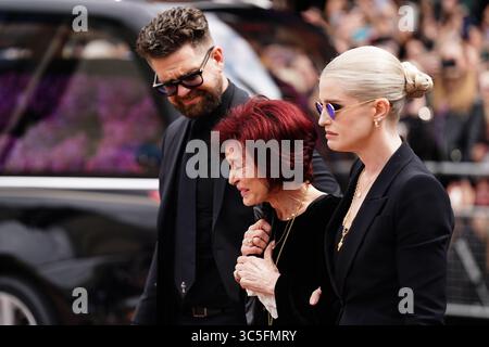 The family of Ozzy Osbourne (left to right) Jack Osbourne, Sharon Osbourne and Kelly Osbourne lay flowers and view the messages and floral tributes left at the Black Sabbath Bridge bench on Broad Street in Birmingham in memory of Black Sabbath frontman Ozzy Osbourne, as his body is brought back to his home city for a procession following his death last week aged 76. Picture date: Wednesday July 30, 2025. Stock Photo