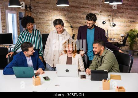 Multi ethnic team collaborating on project using laptop in modern office Stock Photo