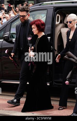 The family of Ozzy Osbourne (left to right) Jack Osbourne, Sharon Osbourne and Kelly Osbourne lay flowers and view the messages and floral tributes left at the Black Sabbath Bridge bench on Broad Street in Birmingham in memory of Black Sabbath frontman Ozzy Osbourne, as his body is brought back to his home city for a procession following his death last week aged 76. Picture date: Wednesday July 30, 2025. Stock Photo