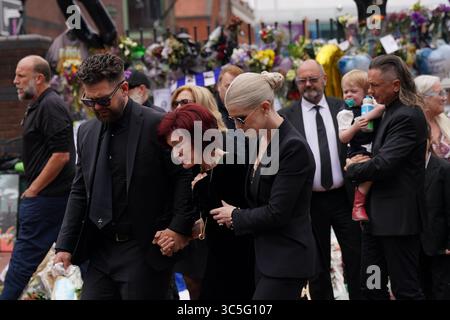 The family of Ozzy Osbourne (left to right) Jack, Sharon and Kelly Osbourne, view the messages and floral tributes left at the Black Sabbath Bridge bench on Broad Street in Birmingham in memory of Black Sabbath frontman Ozzy Osbourne, as his body is brought back to his home city for a procession following his death last week aged 76. Picture date: Wednesday July 30, 2025. Stock Photo