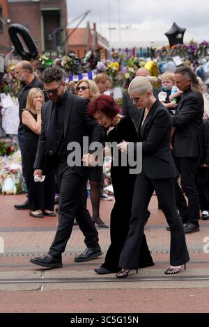 The family of Ozzy Osbourne (left to right) Jack, Sharon and Kelly Osbourne, view the messages and floral tributes left at the Black Sabbath Bridge bench on Broad Street in Birmingham in memory of Black Sabbath frontman Ozzy Osbourne, as his body is brought back to his home city for a procession following his death last week aged 76. Picture date: Wednesday July 30, 2025. Stock Photo