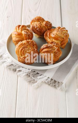 Sticky Braided sweet Knots with pearl sugar closeup on the plate on the table. Vertical Stock Photo