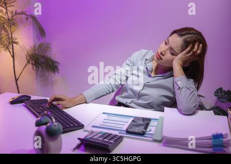 a female supervisor is working overtime at the company stressed because there are many documents that need to be solved in time, tired, businesswoman, Stock Photo