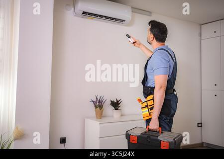 Technician testing air conditioning with remote control Stock Photo