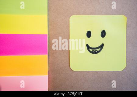 Happy face drawn on colored paper with black marker with a uniform solid background Stock Photo