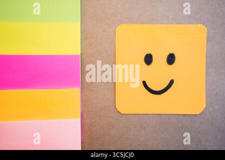 Happy face drawn on colored paper with black marker with a uniform solid background Stock Photo