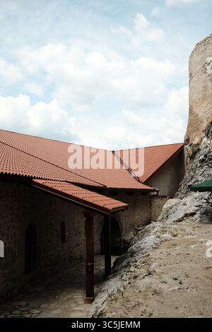 Restored stone buildings with red tiled roofs inside Golubac Fortress blend into the rocky hillside, showing a mix of historical and modern Stock Photo
