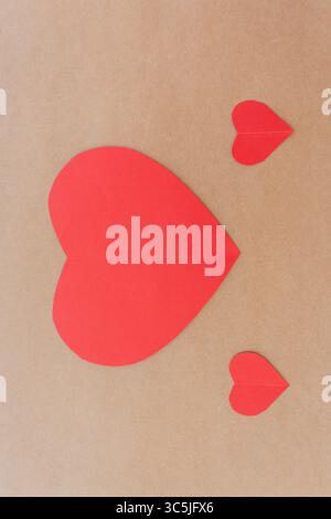 Two paper hearts and smaller heart shapes on a beige surface, love concept. Stock Photo