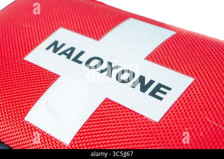 Close-up of a red naloxone pouch showing a white cross and bold black text on textured fabric. Stock Photo
