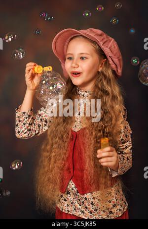 Girl kid with long hair playing with soap bubbles. The concept of a happy childhood Stock Photo