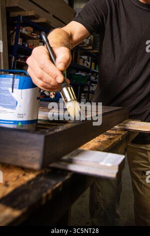 Focused close-up of a craftsman staining a wooden frame in a workshop, symbolizing precision, dedication, and passion for handmade craftsmanship. Stock Photo
