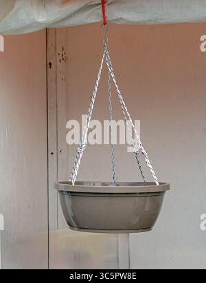Empty plastic flower pot hanging from a ceiling Stock Photo