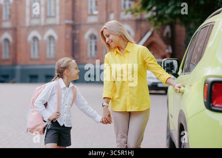 Mother and daughter holding hands walking to school in the morning showing support and love on the first day back. Stock Photo