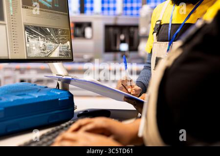 Industry 4.0 engineers designs robotic machinery using CAD software on computer, optimizing industrial automation processes in smart manufacturing plant. Automated factory experts developing machinery Stock Photo