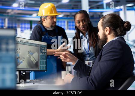 Photovoltaics factory manager working with solar engineering team, improving systems reliability. Alternative energy solar panel manufacturing plant expert providing feedback to workers Stock Photo