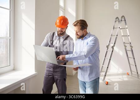 Foreman worker holding laptop and giving consultancy to man Stock Photo