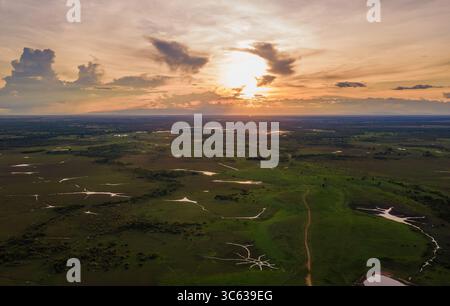 A breathtaking aerial view of Casanare, Colombia, showcasing lush green fields and a stunning sunset over serene waters. Stock Photo