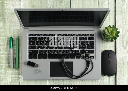 Composition with modern gadgets, pens and houseplant on color wooden background Stock Photo
