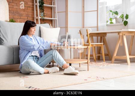 Beautiful woman using laptop on coffee table at home Stock Photo