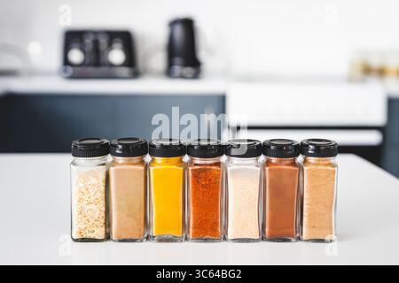 glass jars of garlic, onion, turmeric, paprika, ginger, garam masala and chinese five spice lined up on a kitchen countertop, perfect for cooking, foo Stock Photo