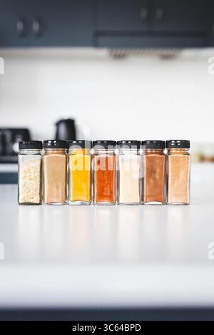 glass jars of garlic, onion, turmeric, paprika, ginger, garam masala and chinese five spice lined up on a kitchen countertop, perfect for cooking, foo Stock Photo
