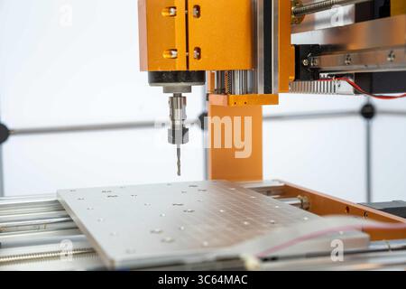 Close-up view of a CNC milling machine with a drill bit working on a metal workpiece. The image showcases precision engineering and advanced manufactu Stock Photo
