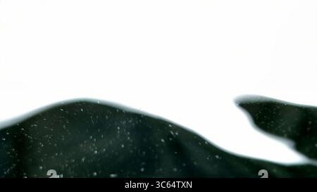 Mesmerizing close-up of a blurred water surface, featuring soft, undulating ripples that form elegant, luminous curves. The dark backdrop accentuates Stock Photo