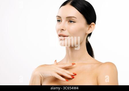 Woman with flawless skin and vibrant red nails poses elegantly against a clean white background, highlighting her beauty and poise in a stunning beaut Stock Photo