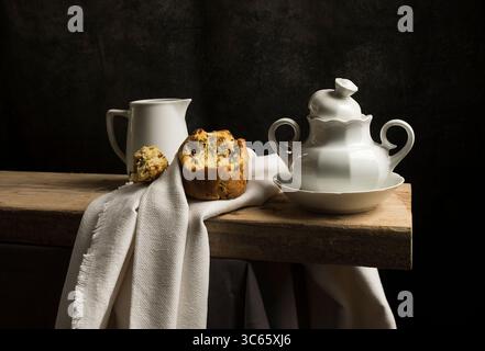 Baroque-style still life with a featuring earthenware teapot and sugar bowl on a wooden board and white tablecloth III, europe Stock Photo