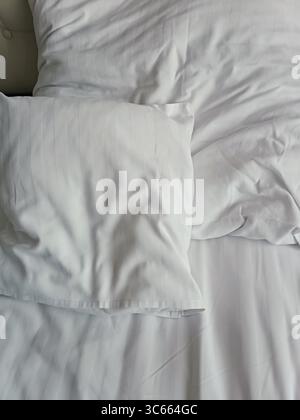 Empty wrinkled white bedding, close up, hotel, white pillows Stock Photo