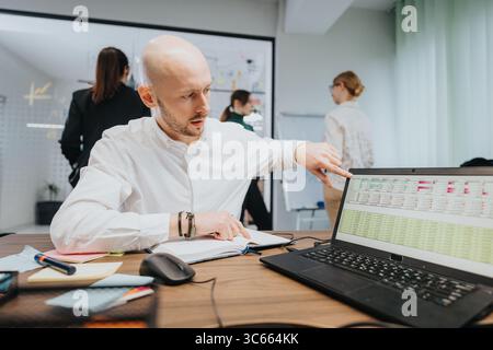 Team collaboration in a modern office environment with team members analyzing data on a laptop Stock Photo
