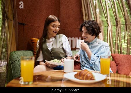 Couple enjoys each others company while relaxing over delicious food and drinks in nature. Stock Photo