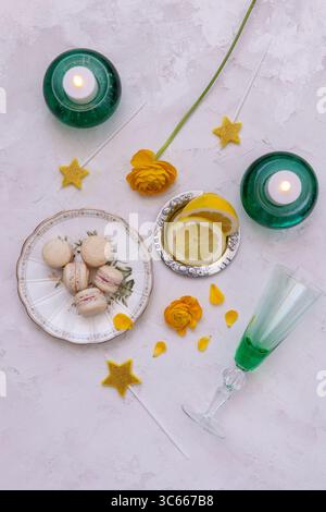 Festive table setting with candles, macarons, lemon and flowers Stock Photo