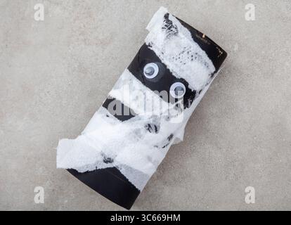 A toilet roll painted black and wrapped with pieces of paper towel. he makes a perfect mummy with just two googly eyes Stock Photo