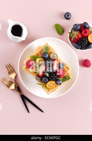 Belgian waffles with fresh strawberry and maple syrup on pink background. Top view.  Stock Photo