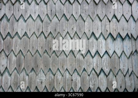 A weathered wooden wall composed of diamond-shaped shingles, evoking a sense of rustic charm and aged textures. Stock Photo