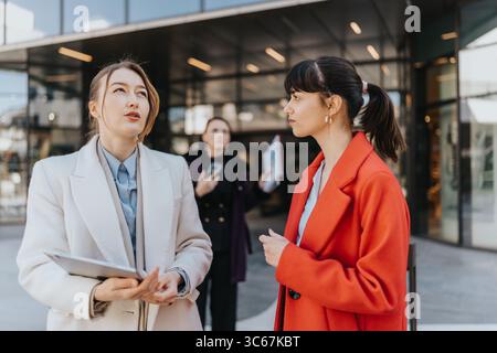Two businesswomen engage in discussion in a modern urban setting Stock Photo